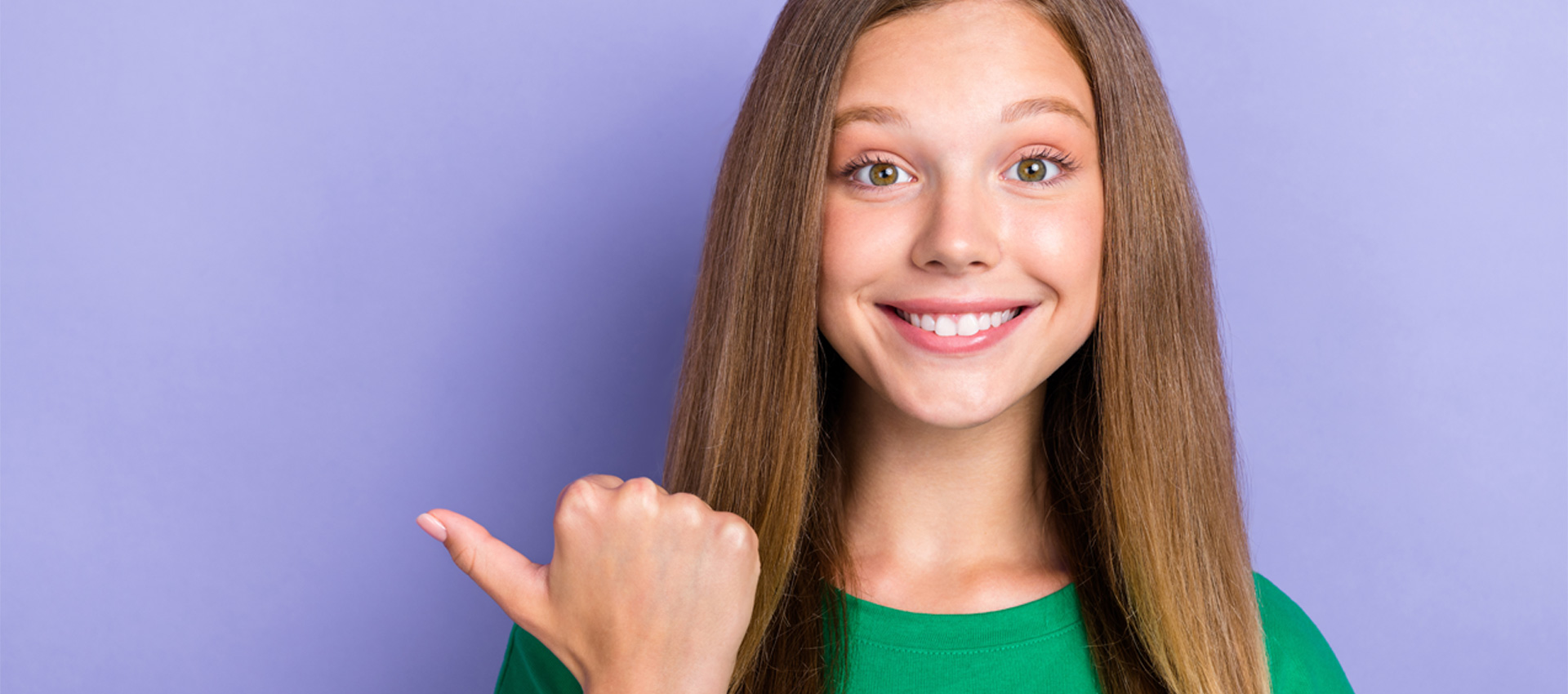 Smiling young woman with long brown hair pointing to the left, promoting Northdene dental services