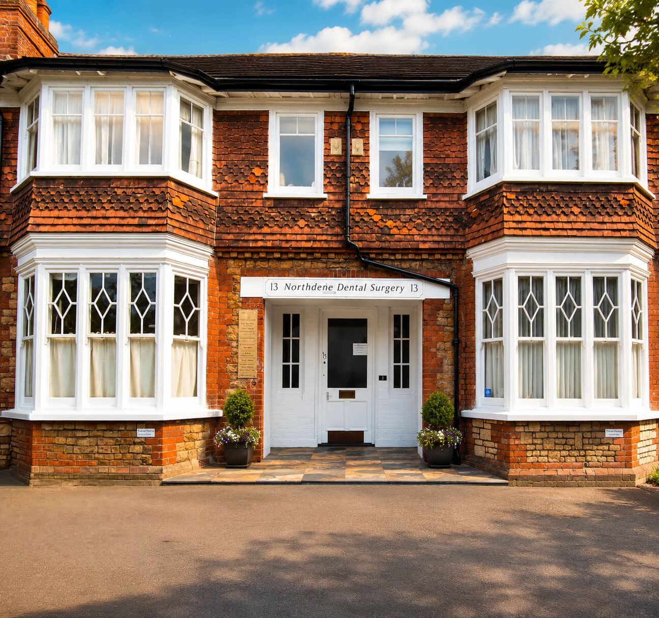 Exterior of Northdene Dental Surgery in Guildford, a red brick building with white bay windows and a central entrance
